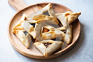 Hamantashen cookies on a wooden board on a gray background. Close up