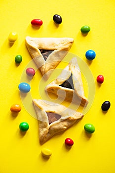 Hamantashen - Festive baking for Jewish holiday of Purim. Traditional cookies with different fillings and candies on a yellow