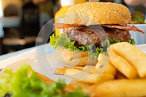 hamburger with bacon served in a white plate with french fries