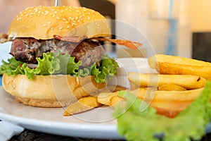 hamburger with bacon served in a white plate with french fries