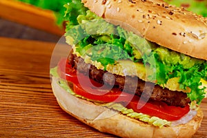 Hamburger with beef, cheese and vegetables on wooden table. Closeup