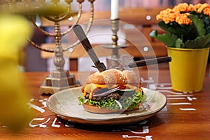 Hamburger with beef, mutton, vegetables, sauce and challah bun, on a plate, side view.