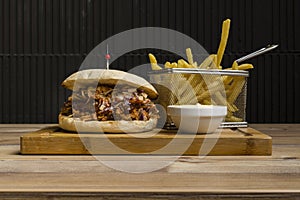 Hamburger with cheese and fried potatoes on a wooden table