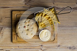 Hamburger with cheese and fried potatoes on a wooden table