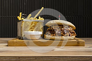 Hamburger with cheese and fried potatoes on a wooden table