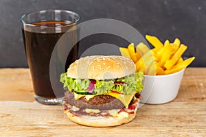 Hamburger Cheeseburger meal fastfood fast food with cola drink and French Fries on a wooden board