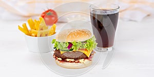 Hamburger Cheeseburger meal fastfood fast food with cola drink and French Fries on a wooden board panorama