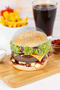 Hamburger Cheeseburger meal fastfood fast food with cola drink and French Fries on a wooden board portrait format