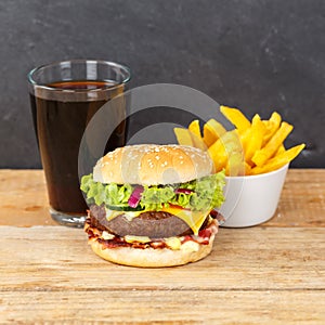 Hamburger Cheeseburger meal fastfood fast food with cola drink and French Fries on a wooden board square