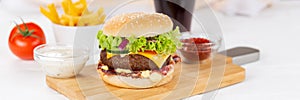 Hamburger Cheeseburger meal fastfood fast food panorama with cola drink and French Fries on a wooden board