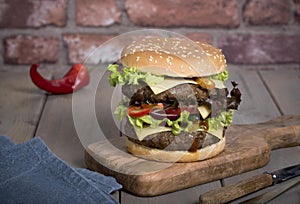 Hamburger with a double serving of meat, tomatoes, salad, onions on a wooden board in a restaurant.Copy space