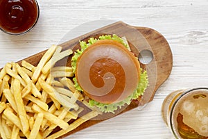 Hamburger, french fries, bbq sauce and glass of cold beer on a white wooden background, top view. Overhead, flat lay, from above