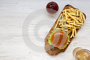 Hamburger, french fries, bbq sauce and glass of cold beer on a white wooden background, top view. Overhead, flat lay, from above.