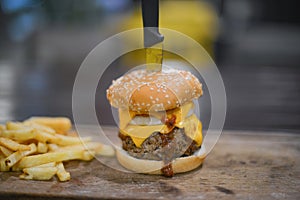 Hamburger, French fries and a Cup of sauce served on a wooden pl