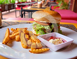 Hamburger, french fries, mayonnaise and ketchup on restaurant background. Yummy fresh burger and french fries