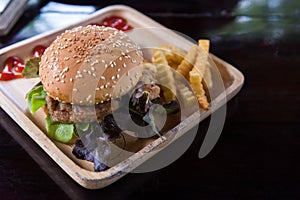 Hamburger with french fries in wooden plate