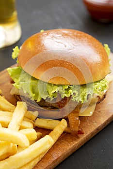 Hamburger with lettuce, cheese and bacon on a rustic wooden board, side view. Closeup