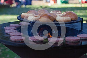 Hamburger meat and buns are grilled on the grill. Outside cooking and barbeque. Meal on the grill. Hamburger patties grilling outd