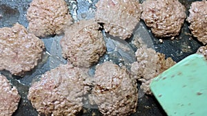 Hamburger patties frying on a griddle spatula flipping meat