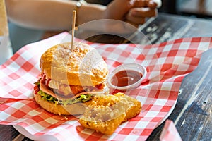 Hamburger set served with hash browns and ketchup on a red and white scotch paper on wooden table looks delicious