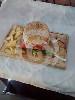 HAMBURGER ON WOODEN TABLE WITH FRIED POTATOES AND SAUCES OF VARIOUS COLORS AND FLAVORS IS A FAST OR CHATARRA FOOD photo