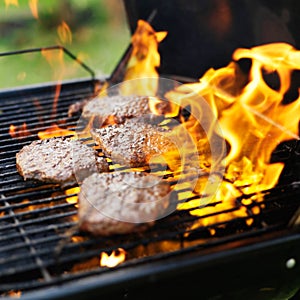 Hamburgers being grilled with flames