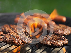 Hamburgers and hotdogs cooking on grill outdoors