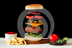 Floating beef burger. Tasty grilled meat with flying food ingredients on a black and white background with homemade ketchup photo