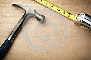 Hamer and measuring tape on wood background