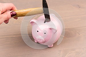 Hammer aiming for pink piggy bank money box on light background. Piggy bank  on wooden background, space for text. Finance, saving
