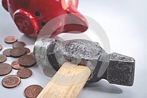 A hammer and a broken red piggy bank, next to a pile of small euro coins. The concept of finding money, shopping, crisis, poverty