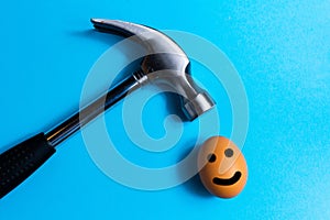 Hammer is hitting on an egg with blue background. minimal idea creative concept.