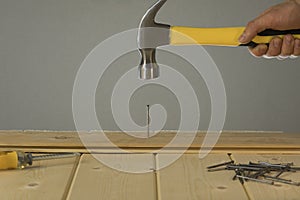 Hammer Hitting Nail On The Head. DIY. Carpenter hands with hammer wood and nail. Using hammer on wood backdrop. Tools for home