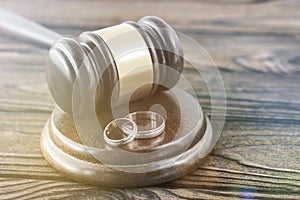 Hammer of a judge, a pair of wedding rings on a wooden background.