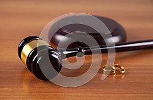 Hammer of a judge, a pair of wedding rings on a wooden background. Family law. Divorce