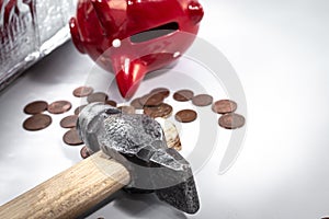 The hammer lies next to a red piggy bank and a bunch of small euro coins. Concept of finding money, shopping, crisis, poverty,