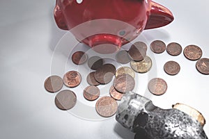 The hammer lies next to a red piggy bank and a bunch of small euro coins. Top view. The concept of finding money, shopping, crisis