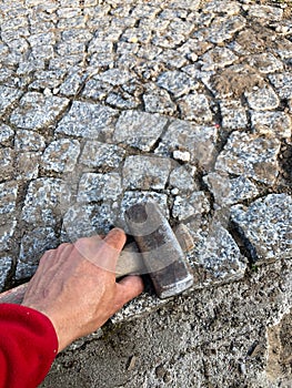 The hammer in the man`s hand on a background of gray paving stones construction tools for physical work macro