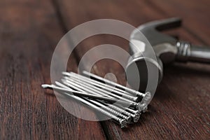 Hammer and metal nails on wooden table, closeup