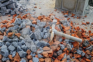 Hammer pickaxe on a pile of stones made from broken red bricks and concrete blocks