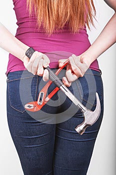 Hammer and pliers behind her back in the hands of a girl