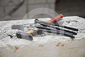 Hammer, pliers and water pump pliers on a piece of masonry as a symbol for construction freeze and construction site