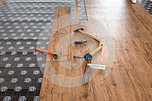 Hammer, ruler with angle bar, tape meter and other tool on laminate vinyl floor