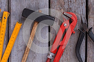 Hammer, ruler and pliers on wooden background.