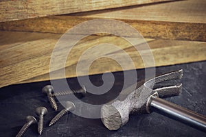Hammer and screw in lumber stacking background.