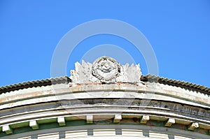 Hammer and Sickle in conjunction with the emblem of the USSR of the concrete on the roof of the old building .