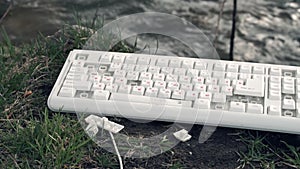 Hammer smashes a computer keyboard. Broken computer keyboard in nature. The concept of technology`s adverse impact on