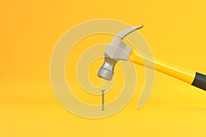 Hammer with a steel head and a yellow plastic handle banging a small screw on yellow background