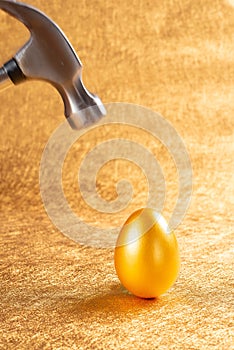 Hammer about to hit a gold egg