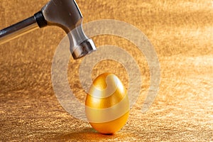 Hammer about to hit a gold egg